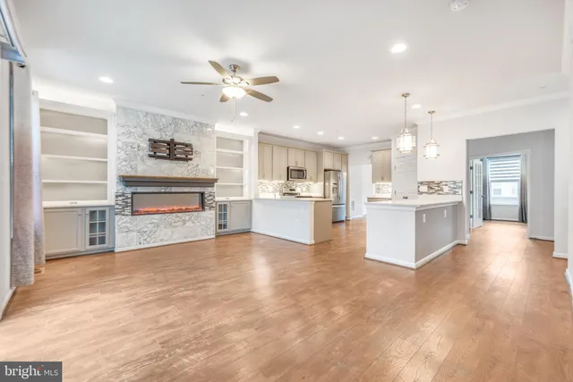 a view of kitchen with kitchen island a stove a sink dishwasher and white cabinets with wooden floor