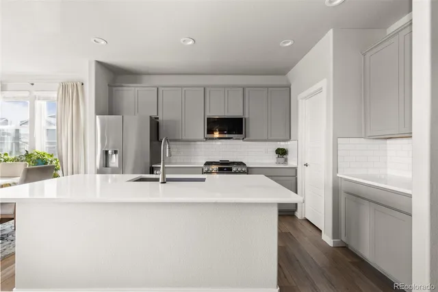 a kitchen with stainless steel appliances a stove refrigerator sink and white cabinets