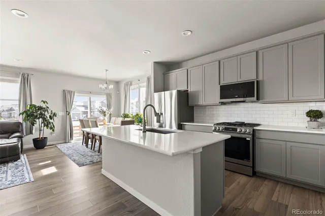 a kitchen with kitchen island a stove a sink a microwave a dining table and chairs