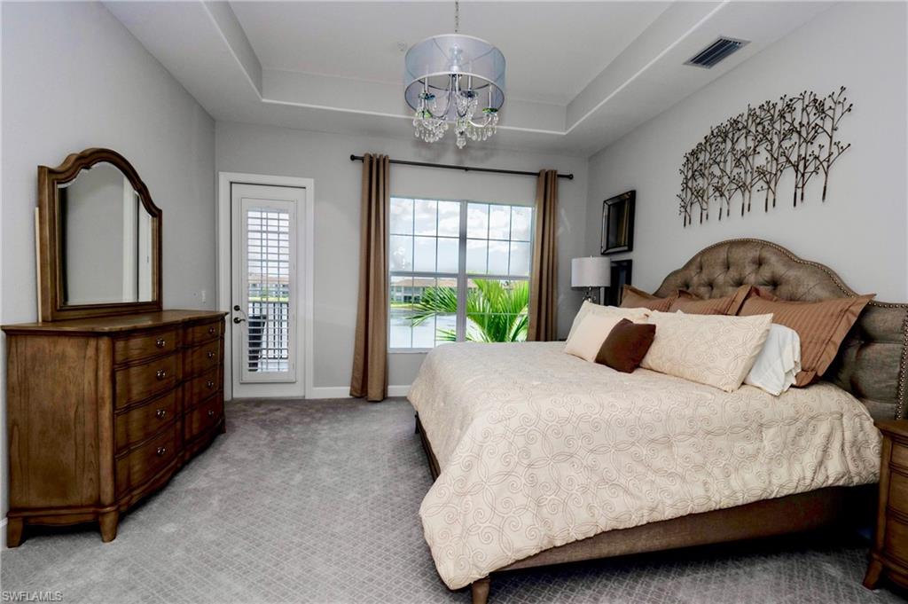 8008 Signature Club Circle Naples, FL 34113 - Photo 19 of 30 a bedroom with a large bed and a dresser next to a window