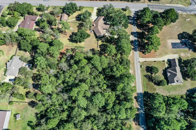 an aerial view of residential house with outdoor space and trees all around