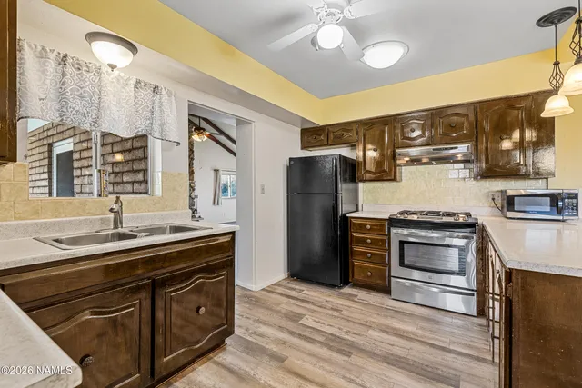 a kitchen with stainless steel appliances granite countertop a refrigerator a sink dishwasher and wooden cabinets with wooden floor