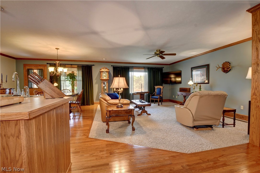 3464 Ridge Road Northwest Strasburg, OH 44680 - Photo 9 of 49 Living room featuring sink, ornamental molding, ceiling fan with notable chandelier, and light hardwood / wood-style floors
