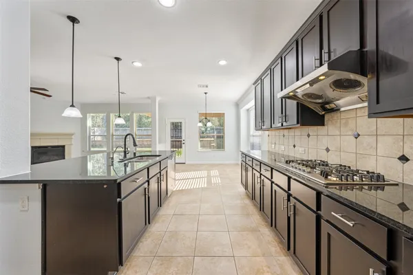 a kitchen with stainless steel appliances granite countertop a sink a stove and a wooden floors