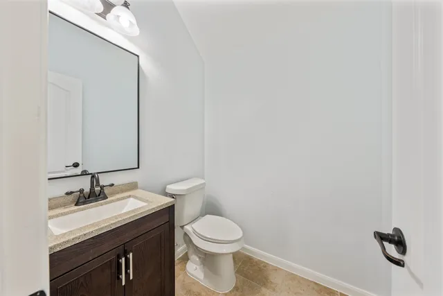 a bathroom with a granite countertop toilet and a sink