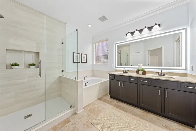 a spacious bathroom with a tub sink shower and mirror