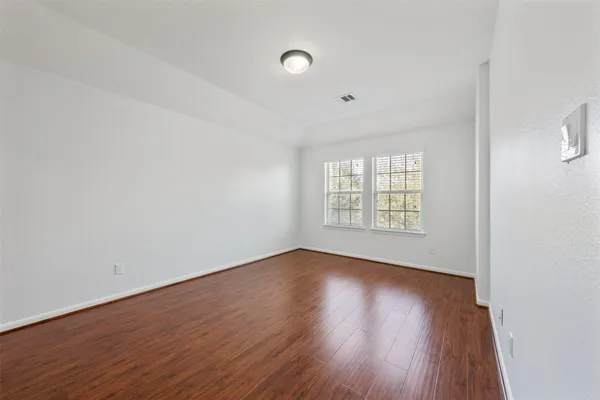 an empty room with wooden floor and windows
