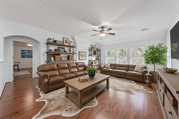 a living room with furniture a chandelier and a wooden floor