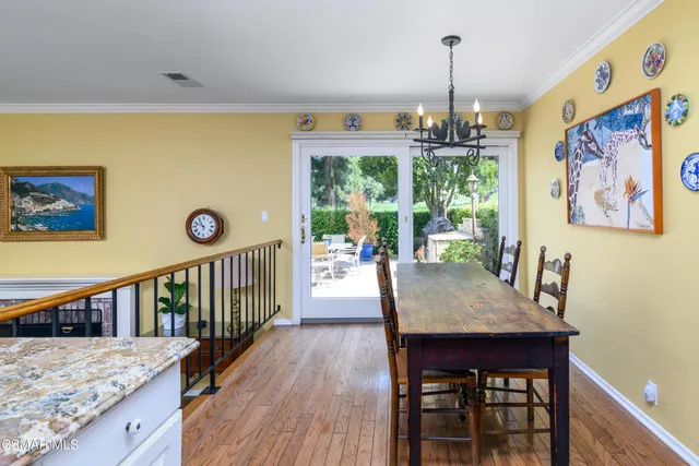 a dining room with wooden floor a chandelier a wooden table and chairs