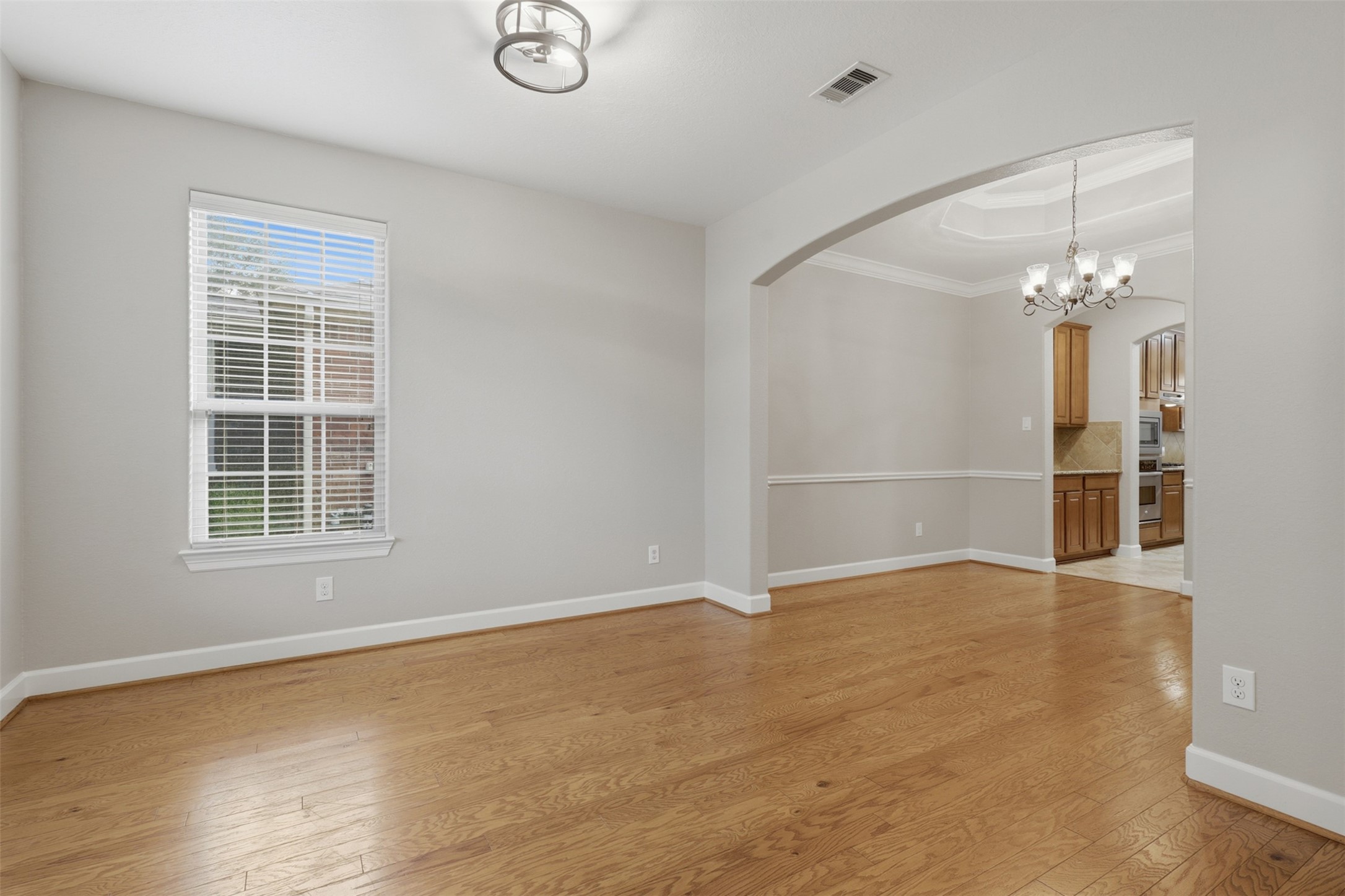 721 Rufina Street League City, TX 77573 - Photo 3 of 33 Designed with flexibility in mind, this spacious living room flows effortlessly into the formal dining area through a dramatic arched opening. Hardwood floors, updated lighting, and expansive windows provide a timeless backdrop for entertaining or everyday living.
