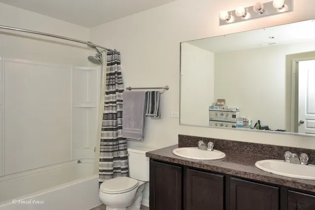 a bathroom with a granite countertop sink toilet mirror and shower