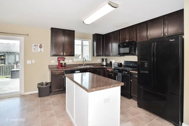 a kitchen with kitchen island granite countertop stainless steel appliances and wooden cabinets