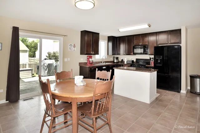 a kitchen with stainless steel appliances granite countertop a stove a refrigerator a kitchen island and chairs