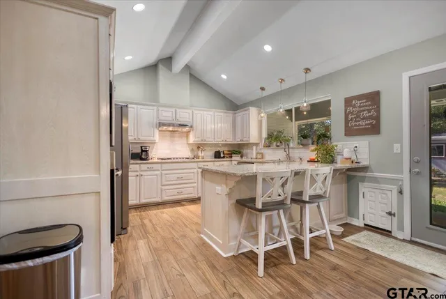 a kitchen with kitchen island wooden floors white appliances and cabinets