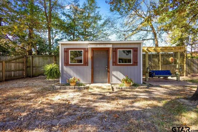 a view of a house with large tree and wooden fence