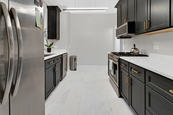 a kitchen with stainless steel appliances granite countertop a refrigerator a sink a stove and oven