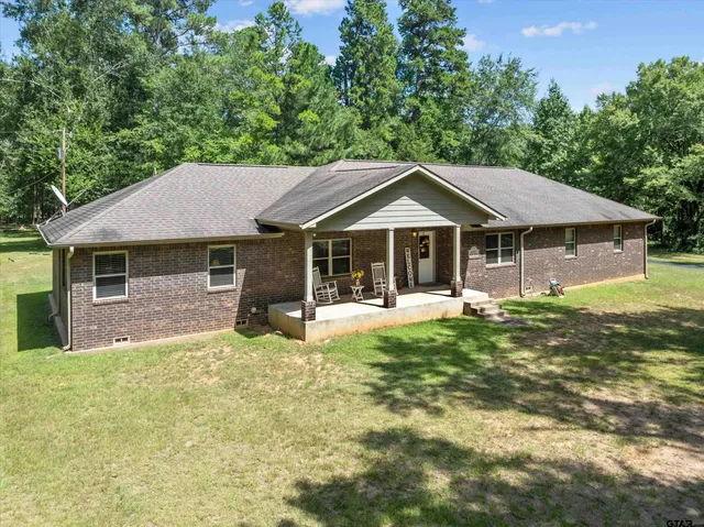 a front view of a house with a garden and trees