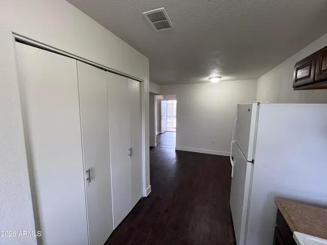 a view of a hallway with wooden floor and a refrigerator