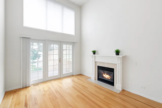 a view of an empty room with wooden floor fireplace and a window