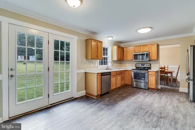 a kitchen with stainless steel appliances granite countertop a stove a sink a refrigerator with wooden cabinets and wooden floor