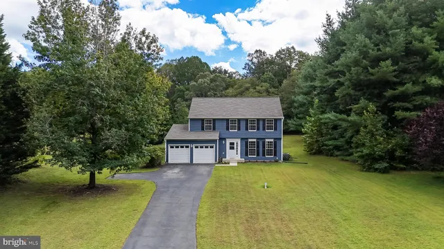 a view of a house with a small yard and large trees