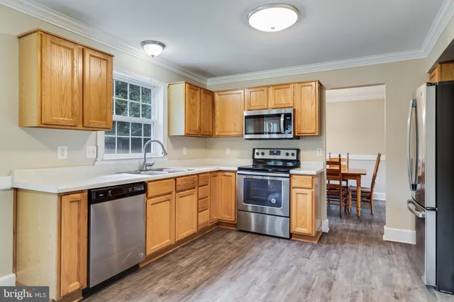 a kitchen with stainless steel appliances granite countertop a stove top oven a sink dishwasher a dining table and chairs with wooden floor