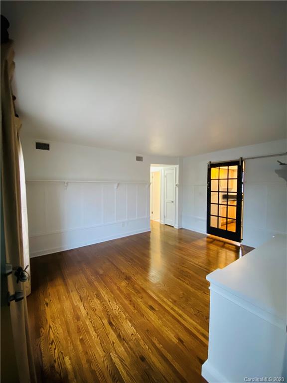 4317 Walker Road, Unit B Charlotte, NC 28211 - Photo 6 of 25 an empty room with wooden floor and windows with curtains