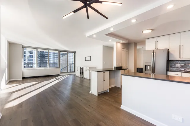 a view of a kitchen with refrigerator and wooden floor