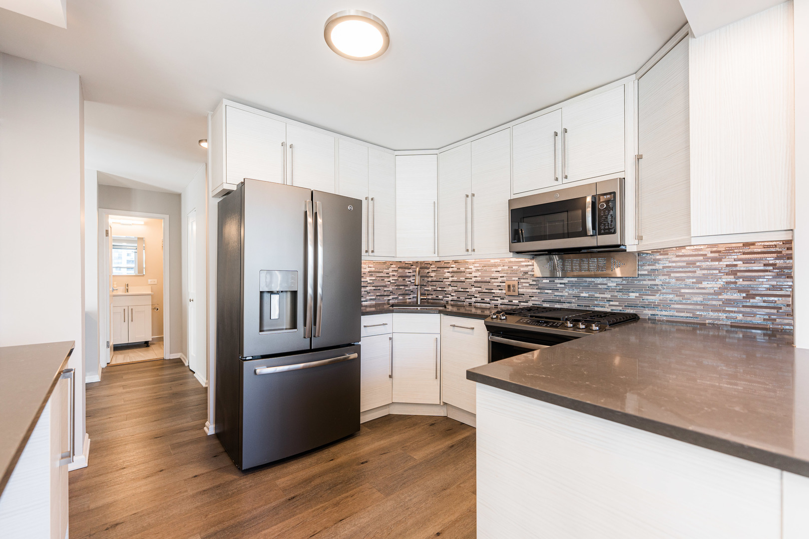 400 East Randolph Street, Unit 3629 Chicago, IL 60601 - Photo 8 of 36 a kitchen with granite countertop a refrigerator a microwave a sink and dishwasher with wooden floor