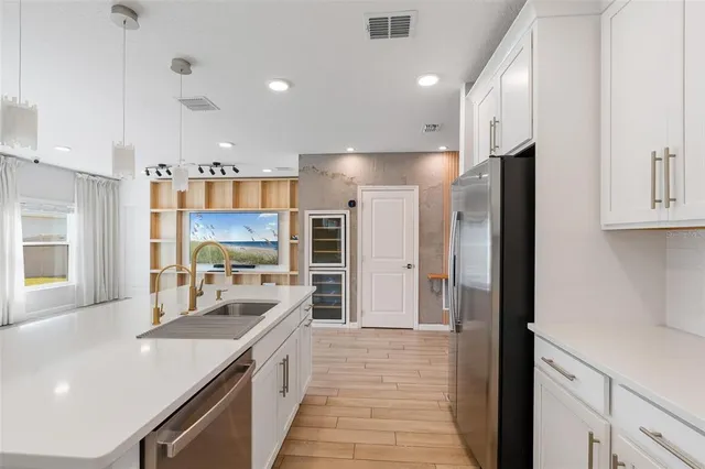 a kitchen with stainless steel appliances granite countertop wooden floors and white cabinets