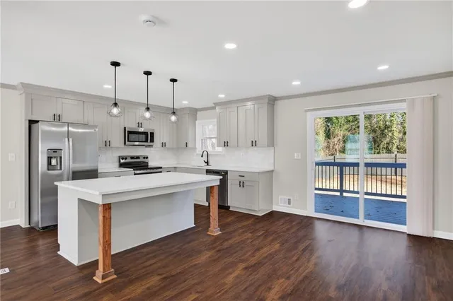 a kitchen with stainless steel appliances kitchen island wooden floors and white cabinets