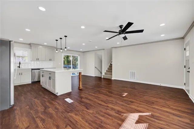 a large kitchen with stainless steel appliances granite countertop a large center island a stove a sink dishwasher and a refrigerator with wooden floor