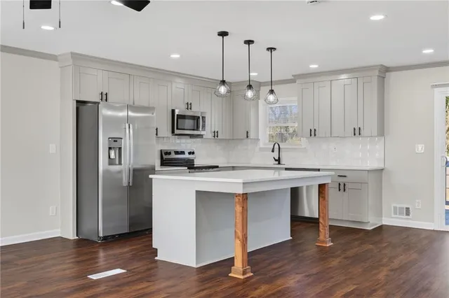 a kitchen with kitchen island granite countertop a sink appliances cabinets and wooden floor