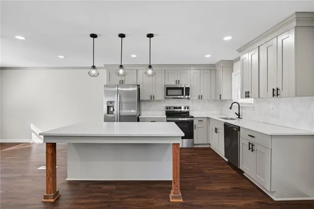 a kitchen with kitchen island a counter top space a sink stainless steel appliances and cabinets