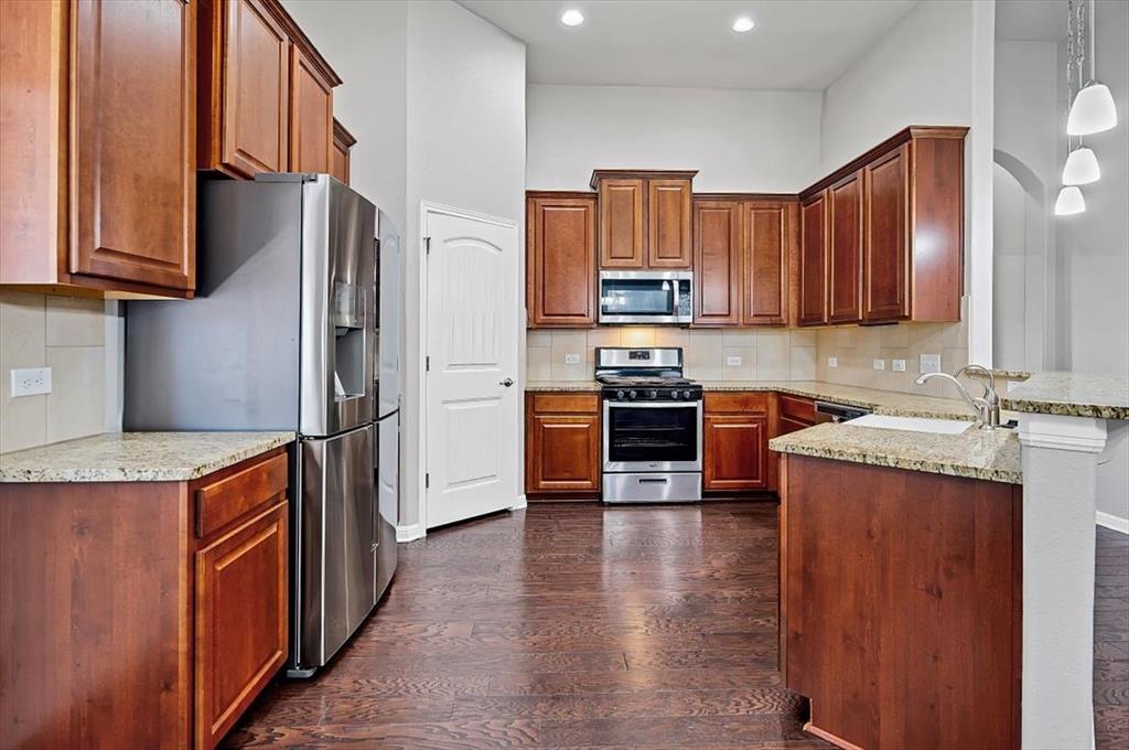 1909 Goldilocks Lane Manchaca, TX 78652 - Photo 6 of 27 a kitchen with stainless steel appliances granite countertop wooden cabinets a stove a sink and a refrigerator