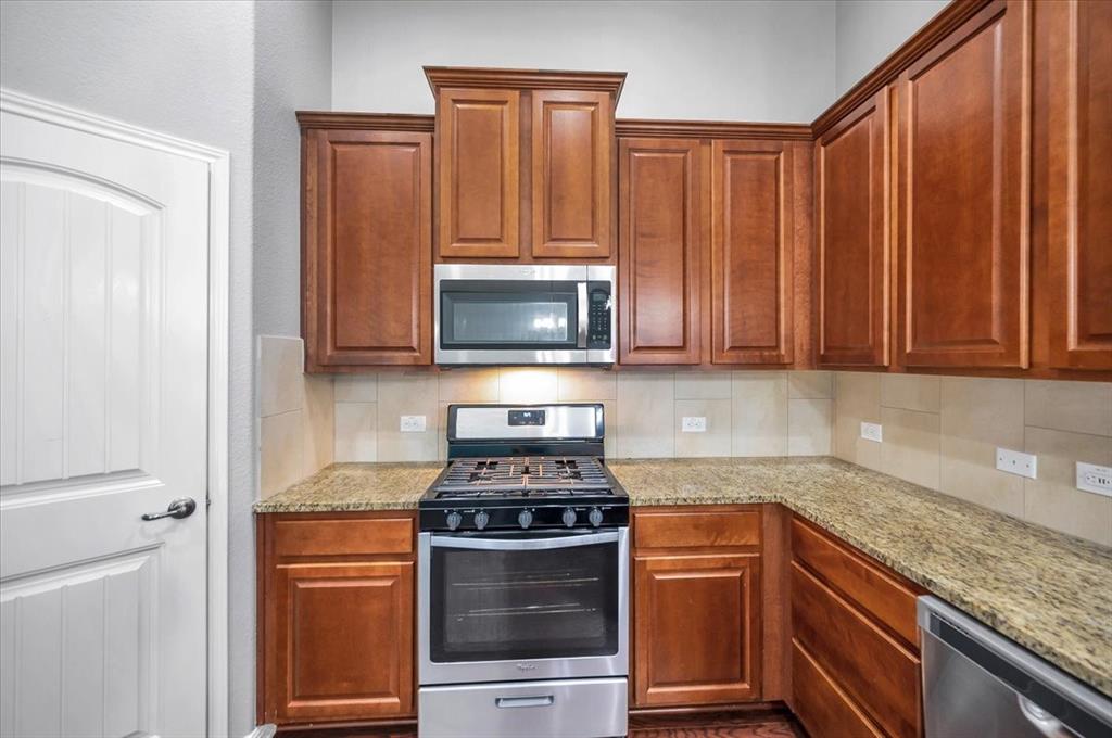 1909 Goldilocks Lane Manchaca, TX 78652 - Photo 8 of 27 a kitchen with granite countertop wooden cabinets and stainless steel appliances