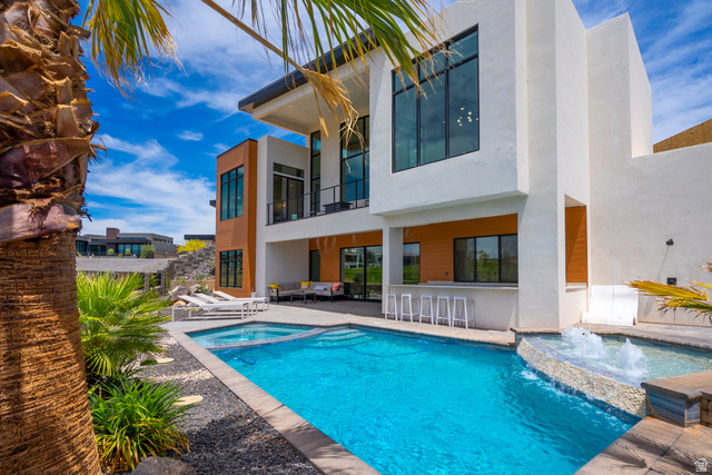 3606 South Cypress Road Hurricane, UT 84737 - Photo 64 of 69 Rear view of house featuring a balcony, stucco siding, a patio area, a pool with connected hot tub, and an outdoor lounge area with bar