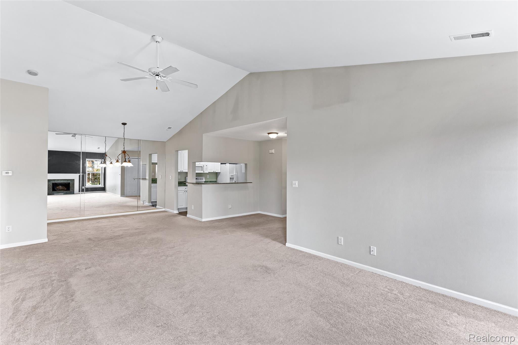 3553 Oakmonte Boulevard Rochester, MI 48306 - Photo 6 of 42 Spacious living area featuring vaulted ceilings, a ceiling fan, and light neutral carpeting