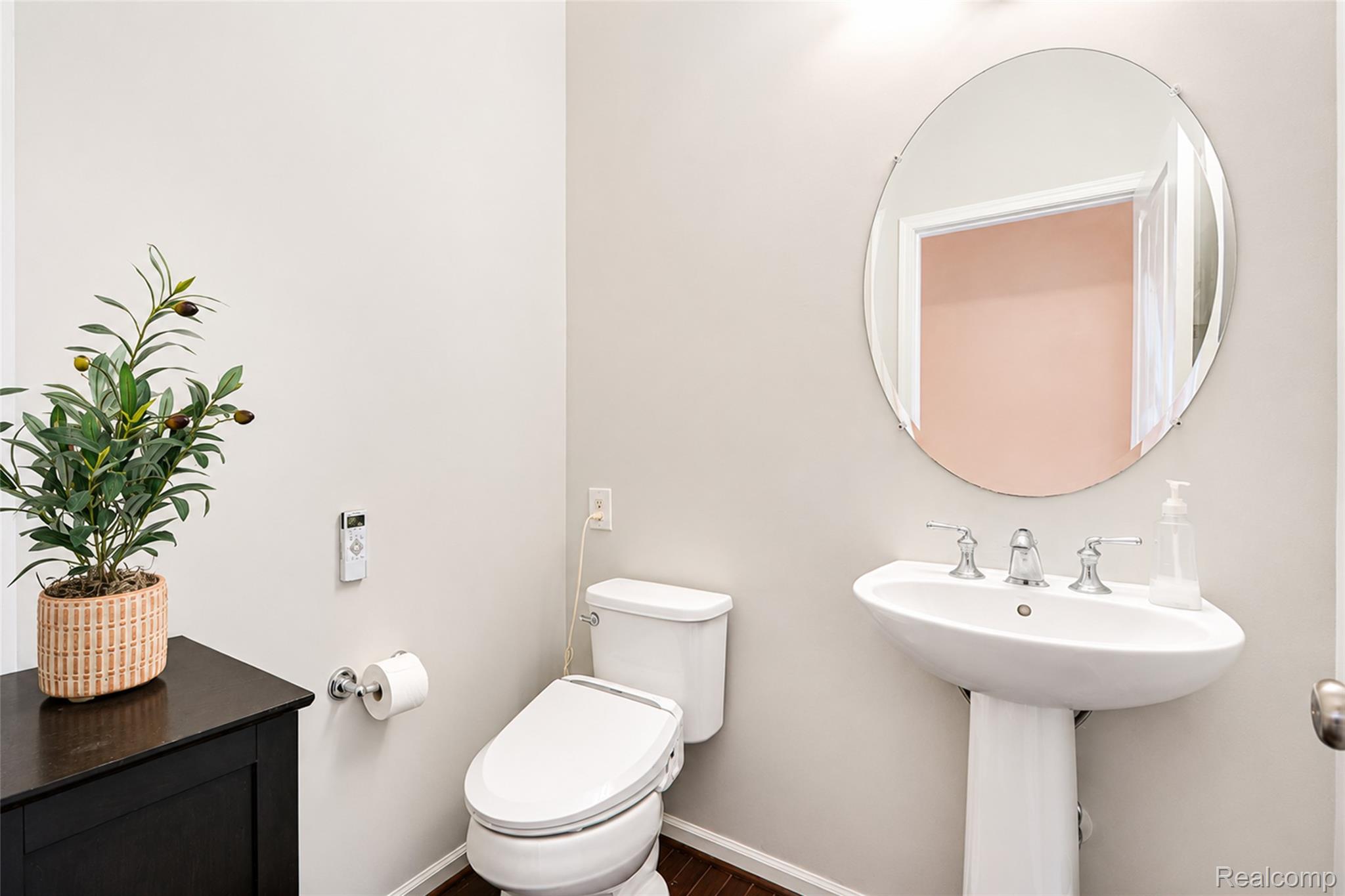 50873 Scarborough Road Canton, MI 48188 - Photo 13 of 33 Pedestal sink with chrome fixtures and an oval mirror, complemented by an adjacent modern toilet