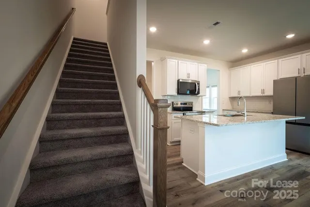 a kitchen with stainless steel appliances granite countertop a refrigerator and a stove top oven