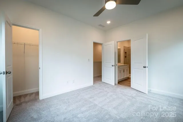 an empty room with closet and a chandelier fan