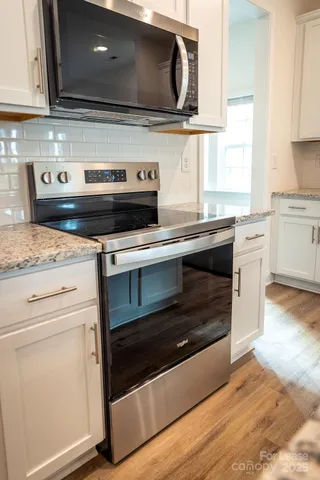 a kitchen with kitchen island granite countertop a sink and a stove top oven with wooden floor