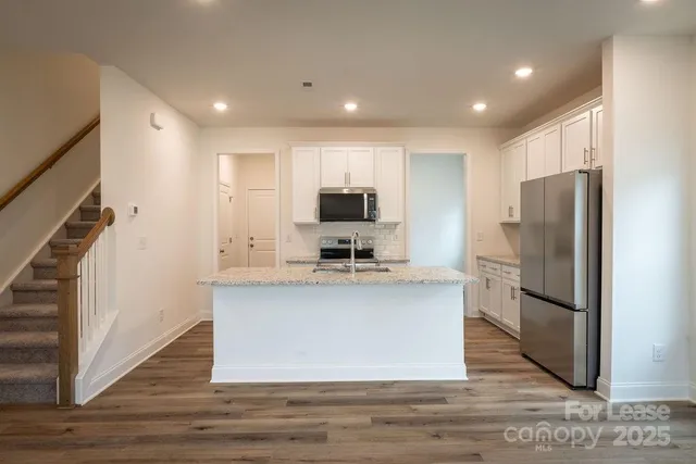 a kitchen with stainless steel appliances granite countertop a refrigerator a sink and a stove