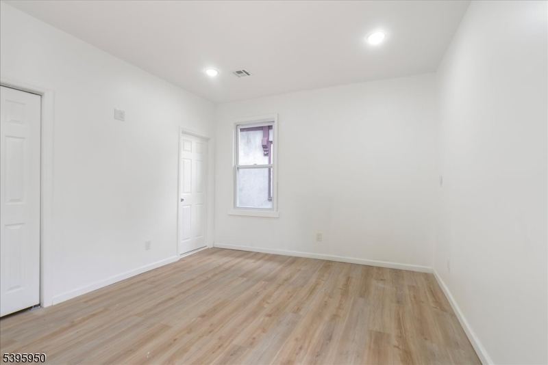 813 South 12th Street Newark, NJ 07108 - Photo 11 of 14 an empty room with wooden floor and window