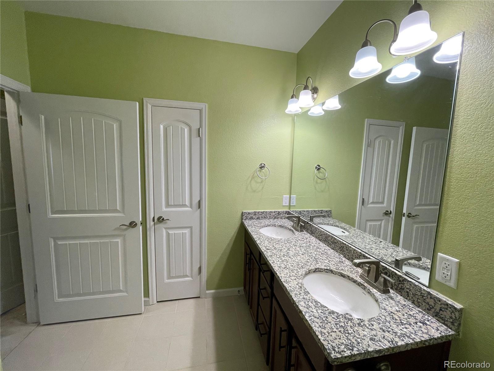 4604 Copeland Circle, Unit 103 Highlands Ranch, CO 80126 - Photo 8 of 11 a bathroom with a granite countertop sink a light fixture and a mirror