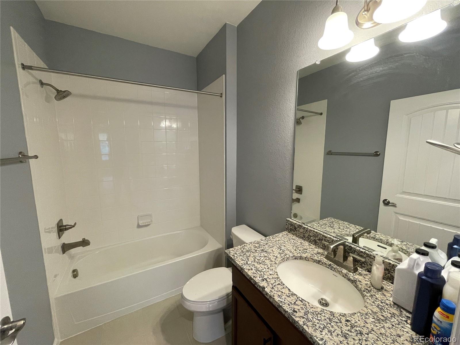4604 Copeland Circle, Unit 103 Highlands Ranch, CO 80126 - Photo 10 of 11 a bathroom with a granite countertop sink toilet mirror and shower