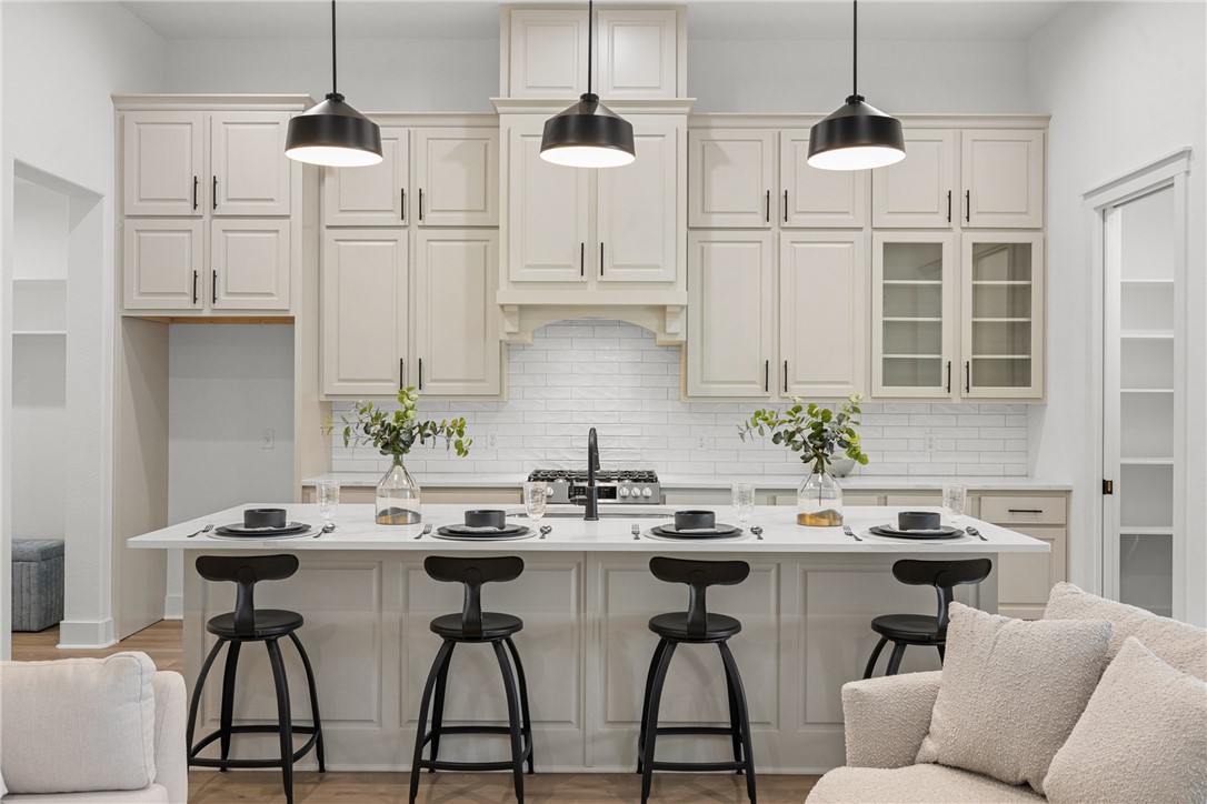 5020 Toscana Loop Bryan, TX 77802 - Photo 8 of 32 a kitchen with stainless steel appliances kitchen island granite countertop a table chairs in it and white cabinets