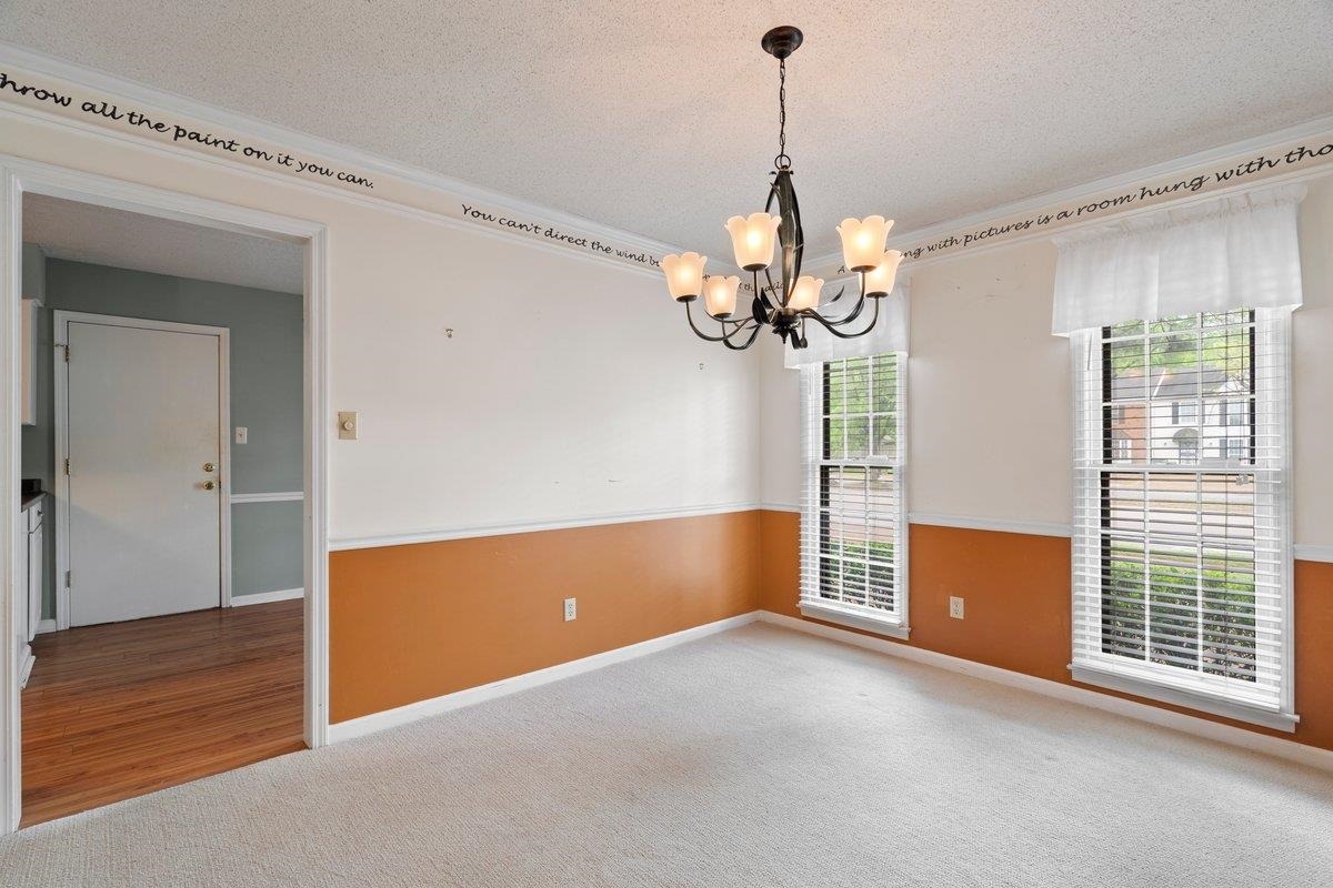 7008 Crestridge Road Memphis, TN 38119 - Photo 4 of 25 Unfurnished room with a textured ceiling, baseboards, a notable chandelier, and carpet floors