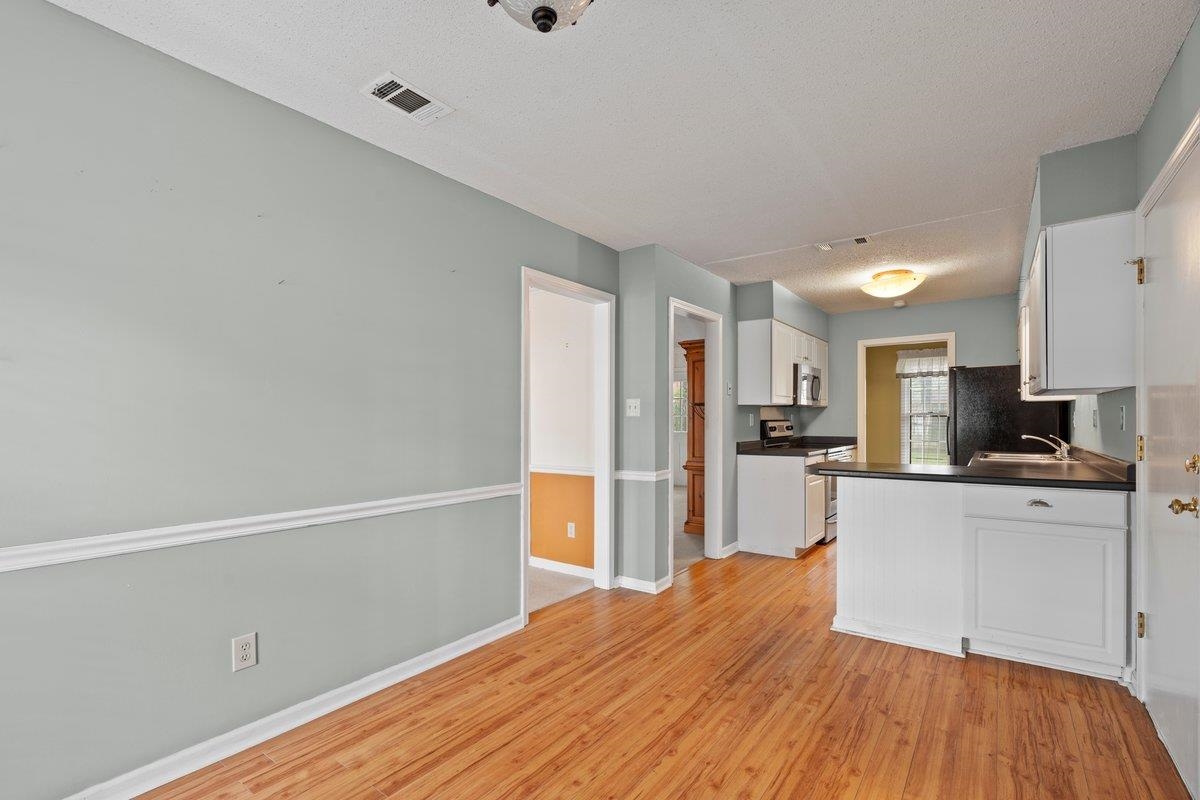 7008 Crestridge Road Memphis, TN 38119 - Photo 5 of 25 Kitchen with appliances with stainless steel finishes, white cabinets, dark countertops, light wood finished floors, and a textured ceiling
