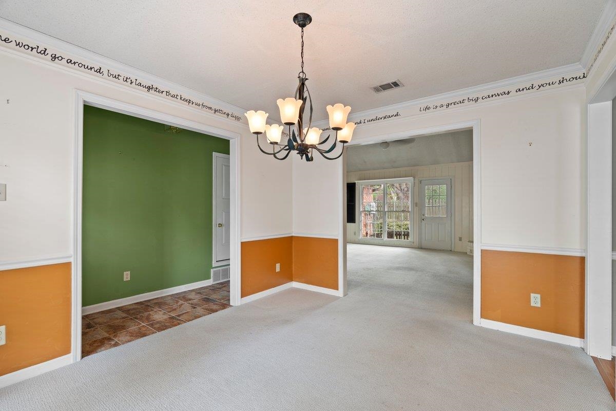 7008 Crestridge Road Memphis, TN 38119 - Photo 7 of 25 Carpeted spare room featuring visible vents, crown molding, a notable chandelier, and baseboards